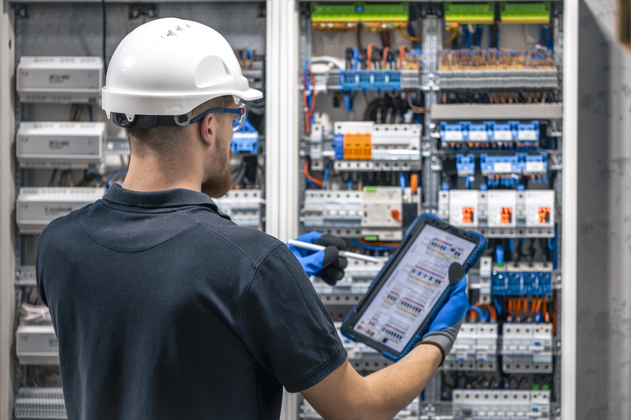 Engineer inspecting a building control panel with a tablet